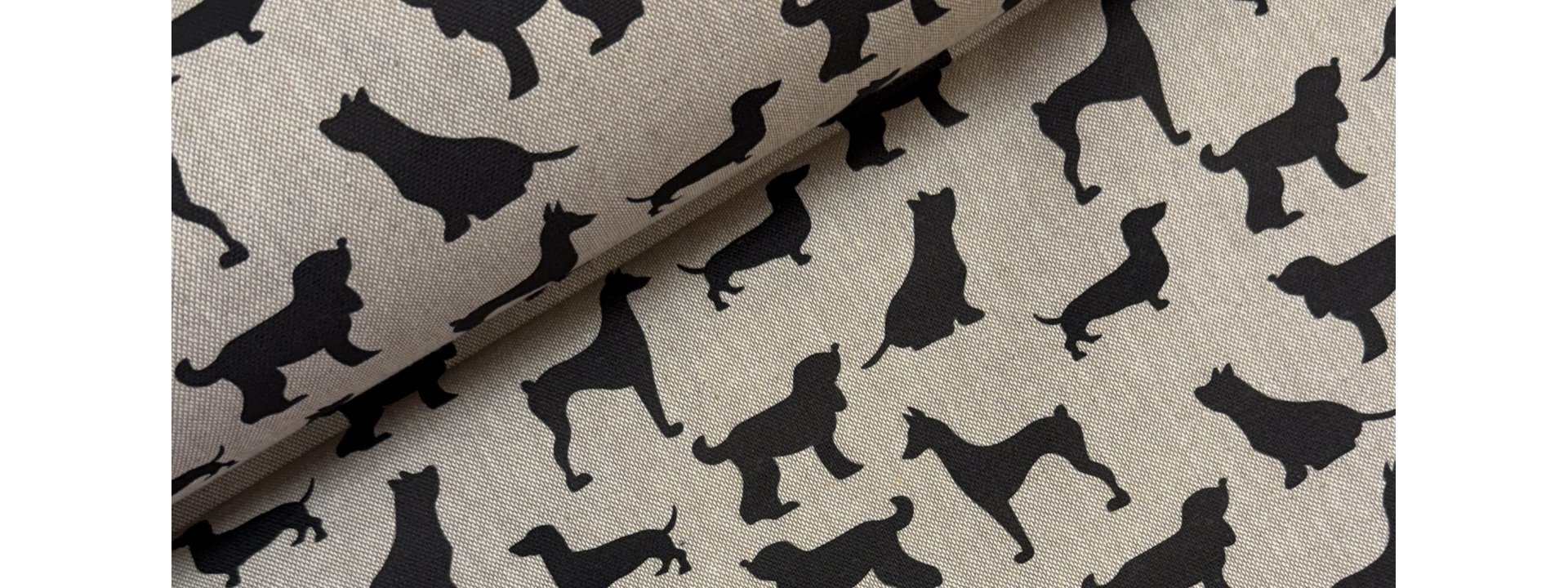 Inredningstyg med svarta hundar på linnefärgad bakgrund.
