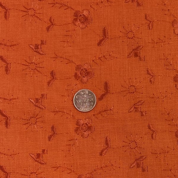 Broderat linne ton i ton, orange. Tygbredd ca 140 cm.